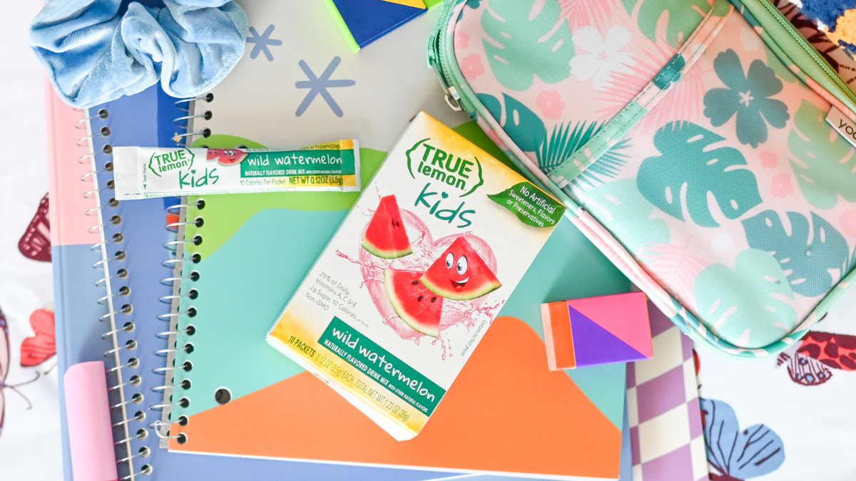 A box of True Lemon Kids Wild Watermelon is on top of an assortment of school supplies such as a pencil pouch and notebooks.