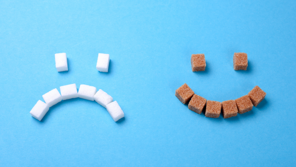 A smile face made of cubes of brown sugar and a frowning face made of cubes of white sugar.