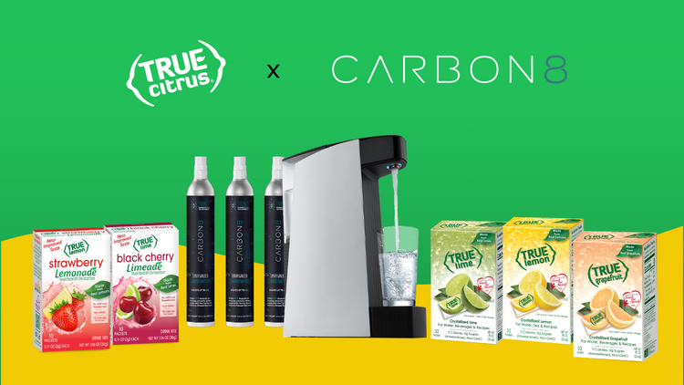 5 boxes of True Lemon products, 3 cannisters of CO2, and 1 Carbon8 machine in front of a green background. There is a yellow wave on the bottom third of the image. The True Citrus and Carbon 8 logo are at the top.