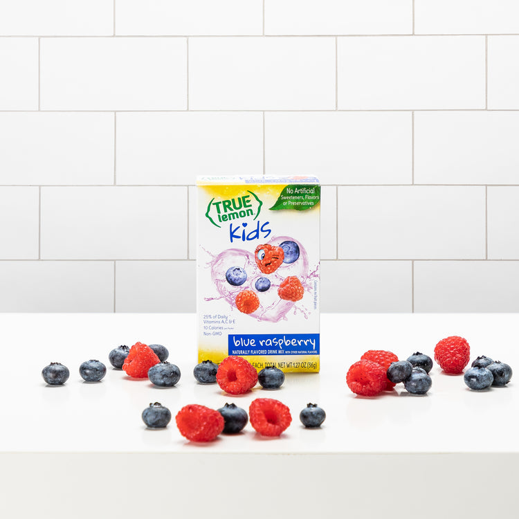 A True Lemon Kids Blue Raspberry box with blueberries and raspberries lying around it.